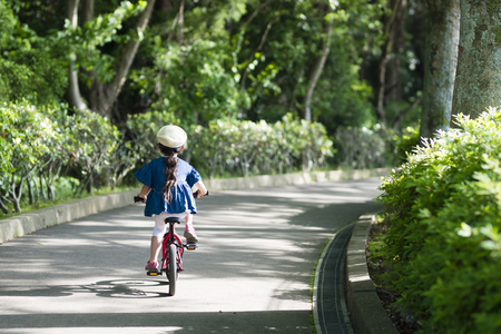 Portrait of a pretty little girl cycling in sunny spring parkの写真素材