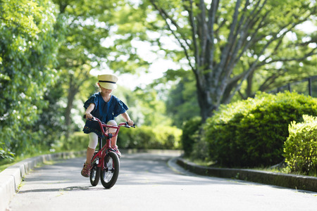 Happy little girl enjoying cycling in sunny springの写真素材