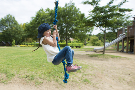 Little girl playing on the tarzan ropeの写真素材