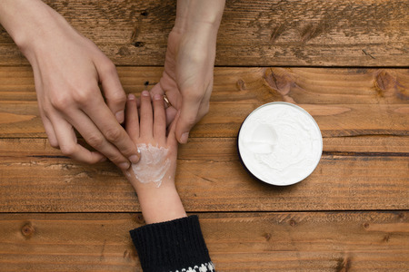 Mother putting hand cream on her child's handの写真素材
