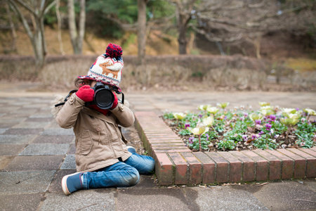 Little girl taking  pictures with digital camera in the parkの写真素材