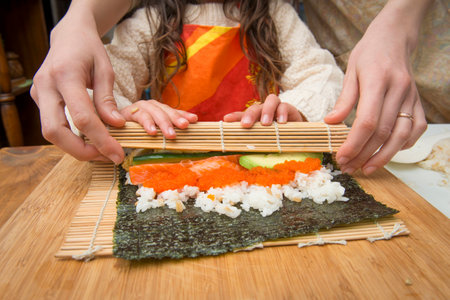 Mother and child making sushi roll togetherの写真素材