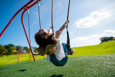 Happy little girl swinging, sky with clouds