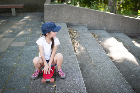 Pretty little girl sitting on a skateboardの写真素材
