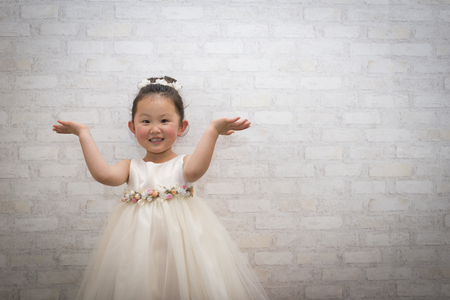 Pretty little girl in a white dress with white backgroundの写真素材