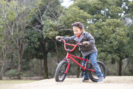 Little girl riding on the bicycle on a cold winter dayの写真素材
