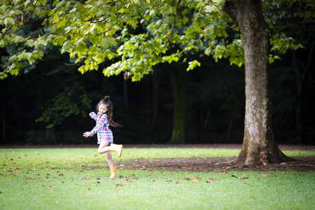 Girl wearing rain boots dancing in the green lawnの写真素材