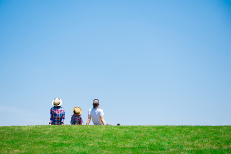 Father and mother and daughter sitting in the meadowの写真素材