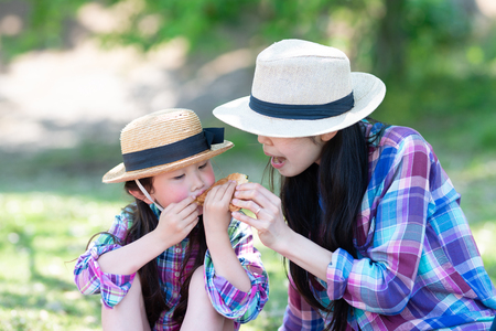 Mother and daughter eating sandwich at lunchtimeの写真素材