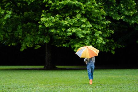 Cute girl walking with umbrellaの写真素材