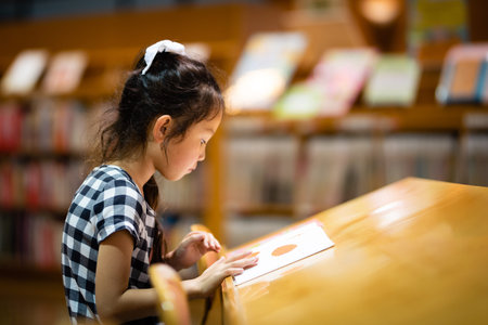 Girl reading a book in the libraryの写真素材