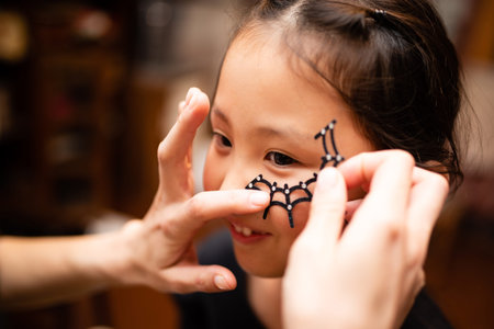 mother helps girl to dress up for Halloween