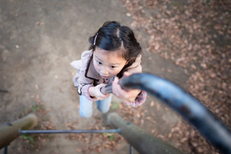Girl climbing climbing pole in autumn park