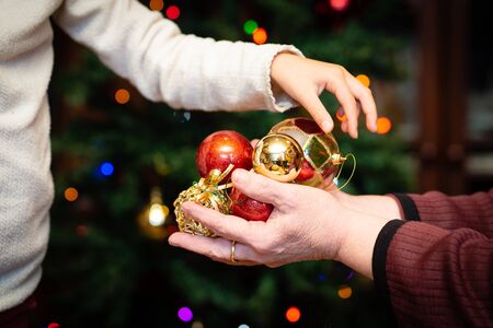 Grandmother and granddaughter handing over Christmas tree decorationsの写真素材