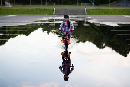 Girl riding a bicycle in a puddleの写真素材