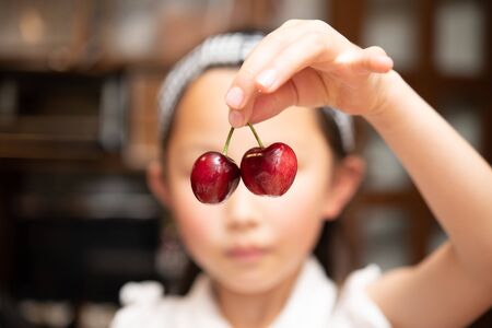 Girl picking up with a cherryの写真素材