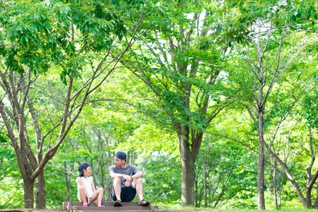 Father and daughter sitting and talking in the woodsの写真素材