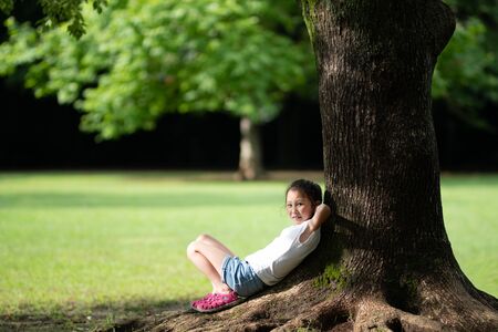 Girl relaxing in the shade of a treeの写真素材