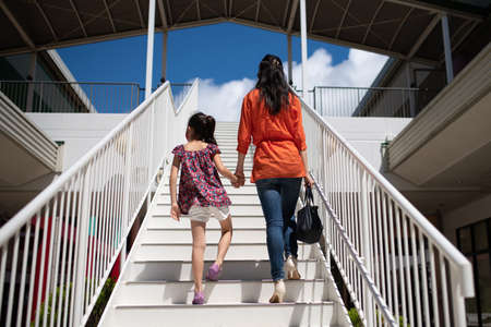 Mother and daughter holding hands and climbing stairsの写真素材