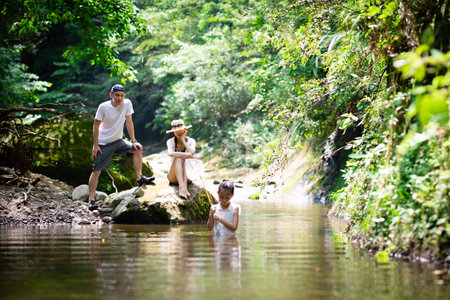 Father, mother and daughter playing in the mountain stream