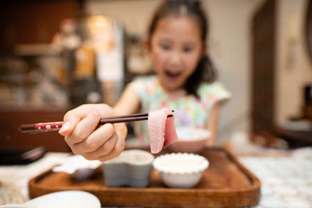 Child eating sashimi with chopsticksの写真素材