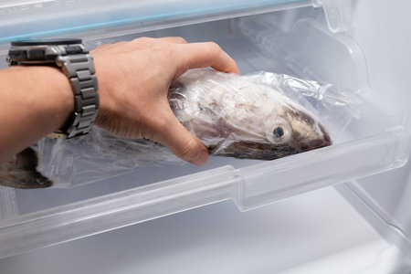 Hand touching the fish in the refrigerator