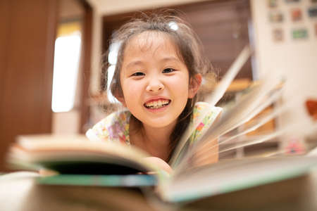 Girl lying down and reading a bookの写真素材