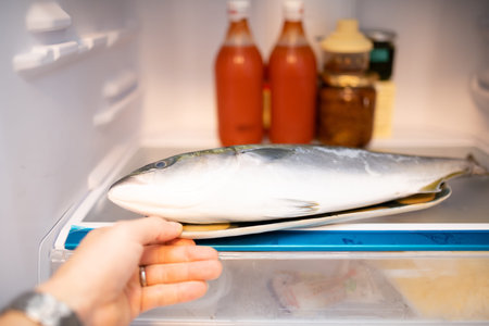 Hand trying to take out the fish in the refrigerator