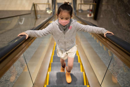 Girl wearing a mask and riding an escalatorの写真素材