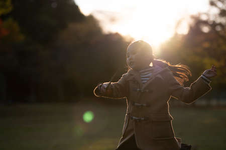 Girl playing in the park at sunsetの写真素材