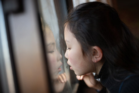 Girl blowing breath on the window glassの写真素材