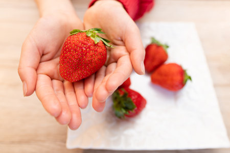 Girl's hand holding a strawberryの写真素材