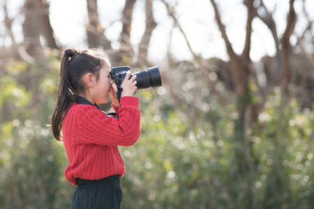 A girl taking a picture with a single-lens reflex cameraの写真素材