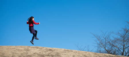 Girl jumping under the blue skyの写真素材