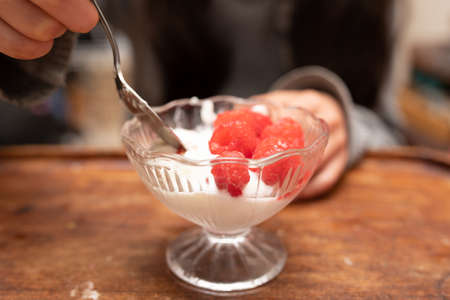 A child eating yogurt with raspberriesの写真素材