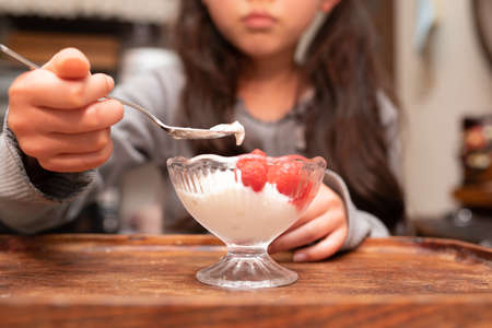 A child eating yogurt with raspberriesの写真素材