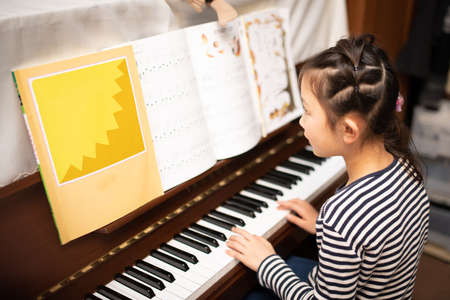 Girl playing the piano at homeの写真素材