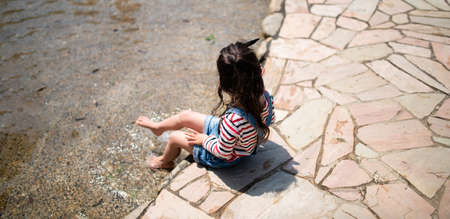A child playing barefoot in the waterの写真素材