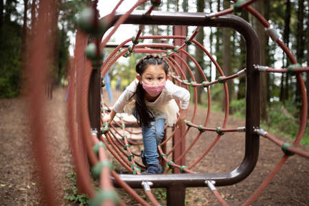 A child wearing a mask and playing in the parkの写真素材