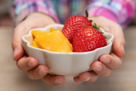 Child's hand holding a bowl of fruit
