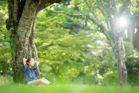 Girl sitting on a tree in the forestの写真素材