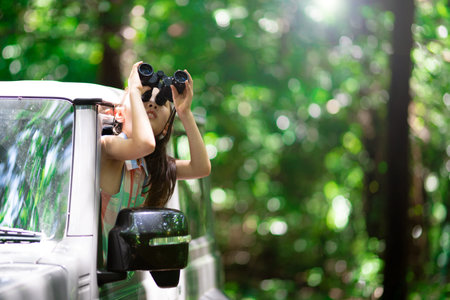 A child leaning out of a car window and using binoculars