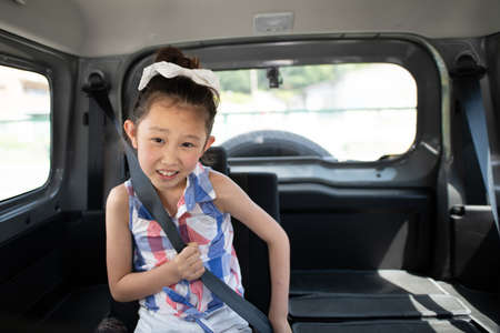 Girl wearing a mask sitting in the back seat of a carの写真素材