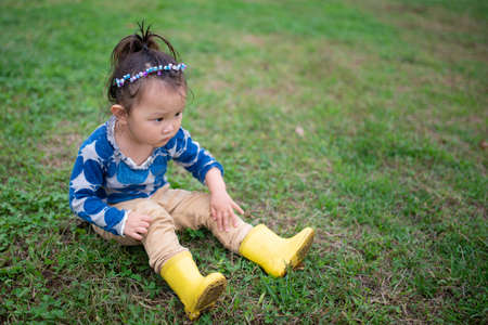 Girl in boots sitting on the lawnの写真素材