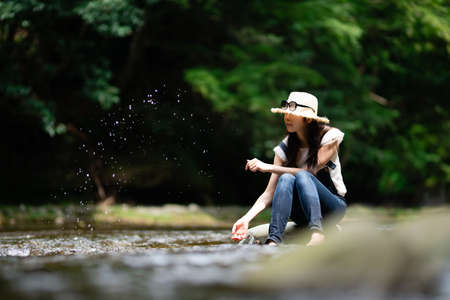 A woman sitting on a rock in a mountain stream and relaxingの写真素材