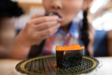 Child eating sushi rolls of fish eggsの写真素材