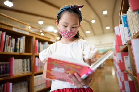 Girl wearing a mask and reading a bookの写真素材