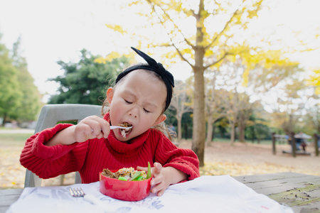 Little girl eats lunch in the park