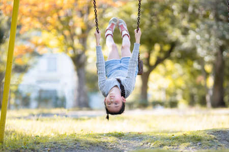 Girl swinging in the autumn parkの写真素材