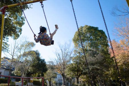 A girl swinging a swing high in the skyの写真素材
